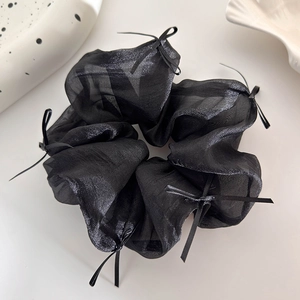 Dettaglio di un elastico per capelli in organza nera con eleganti fiocchi in nastro