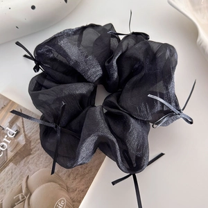 Dettaglio dell'elastico in organza nera con pieghe a strati e piccoli fiocchi