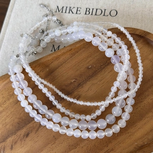 Close-up of white agate beaded necklaces on a wooden tray with metal lobster clasps