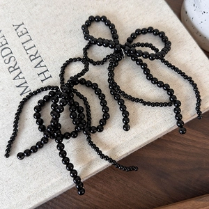 Détail de breloque chaussure nœud perles noires avec longues franges sur livre