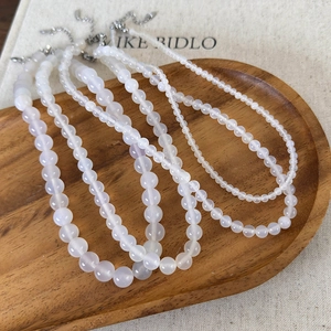 Natural white agate beaded necklaces in various bead sizes on a wooden tray