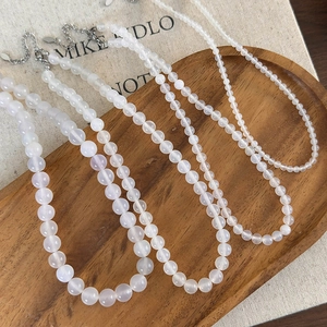 Detailed view of four beaded white agate necklaces with adjustable silver lobster clasps