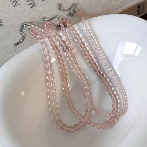 Pink translucent beaded necklaces with silver clasps on white ceramic bowl
