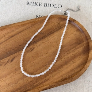 Detail of beaded agate necklace with silver lobster clasp on a vintage wooden tray
