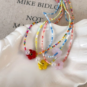 Colorful beaded mermaid flower necklace for women in shell tray on a beige fabric