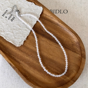 Close-up of white agate beaded necklace with silver extension chain on wooden tray
