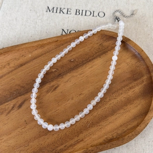 Detail of translucent white agate beaded necklace resting on an elegant wooden tray