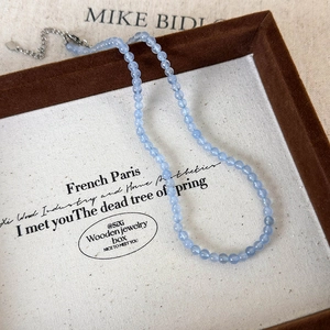 Detail of light blue beaded necklace with faceted stone texture and silver metal clasp