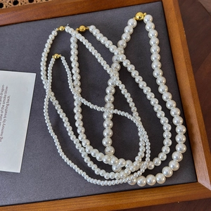 Elegant multi-layer white pearl necklace with golden magnetic clasp on display