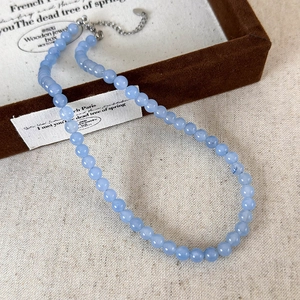 Detail of light blue beaded stone necklace with silver lobster clasp on jewelry box