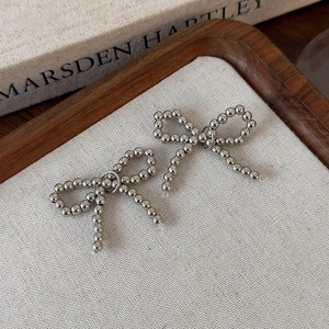 Détail de nœuds de perles argentées pour chaussures sur tissu avec plateau en bois