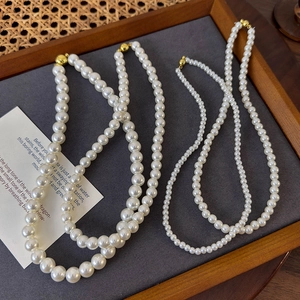 Elegant white round pearl necklace set with gold magnetic clasps on jewelry display