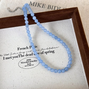 Detail of light blue faceted beaded necklace with silver adjustable chain in a jewelry box
