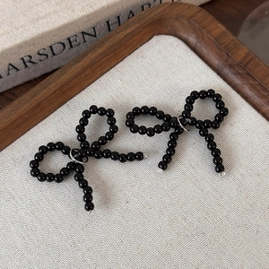 Détail de breloques de chaussures avec nœuds en perles noires et anneaux argentés