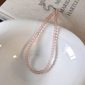 Detailed shot of pink beaded necklace with silver lobster clasp on a white ceramic bowl