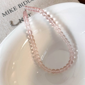 Close-up of transparent pink glass beads with silver metal clasp on a textured background