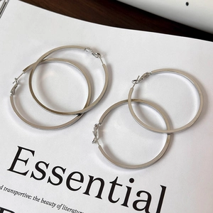 Minimalist silver large hoop earrings set on a white magazine background for women