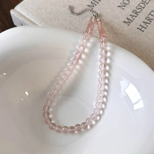 Detailed view of pink beaded glass necklace in a white bowl with silver lobster clasp