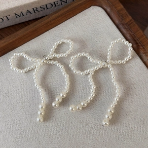 Détail de breloques de chaussures en perles blanches en forme de nœud sur lin
