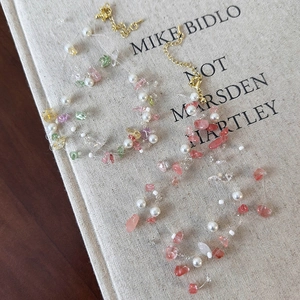 Handmade necklace with natural pink stones, pearls, and golden lobster clasp on a book surface