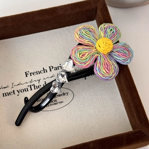 Vue détaillée d'une pince à cheveux fleur tissée arc-en-ciel avec strass en forme de cœur