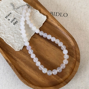 Macro detail of natural translucent white agate beaded necklace on a vintage wooden tray