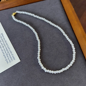 Detailed macro view of white round pearls with a golden magnetic spherical clasp