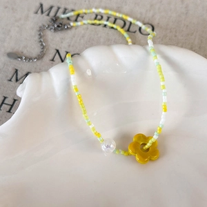 Detail of colorful beaded choker necklace with a yellow flower pendant on a shell tray
