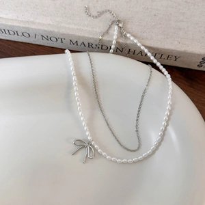 Collana a doppio strato con piccole perle e ciondolo a fiocco su piatto di ceramica
