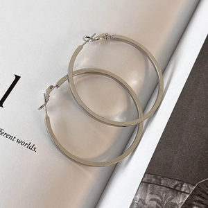 Close-up of minimalist silver hoop earrings with polished mirror finish on white paper
