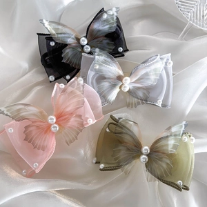 Elegant butterfly hair clips set with pearls on silk background in four soft pastel colors