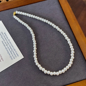 Detailed macro view of white round pearls with a shiny gold spherical magnetic clasp