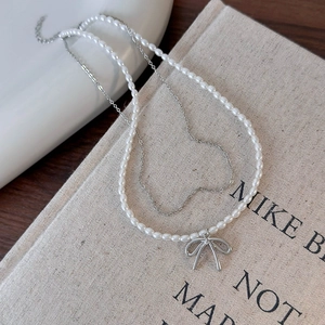 Dettaglio di una collana di perle a due strati con ciondolo a fiocco argento su libro