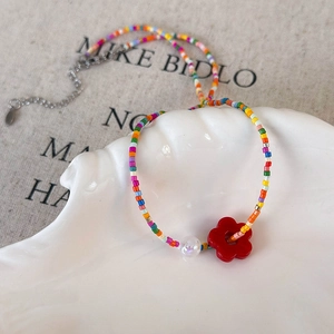 Macro shot of colorful beaded flower necklace on a white seashell tray with lobster clasp