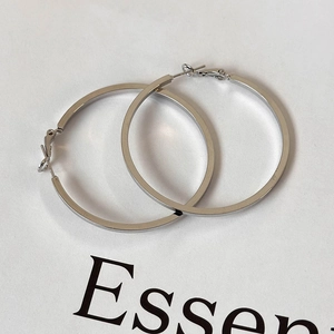 Detailed view of silver flat hoop earrings with secure latch back closure on display card