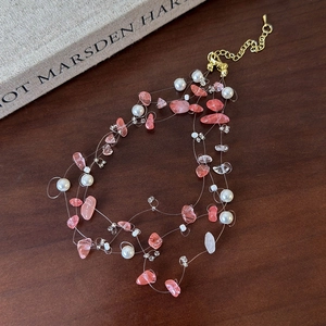 Detail of multi-layer pink natural stone and pearl necklace with golden extender chain