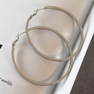 Macro shot of large polished silver hoop earrings on a clean minimalist magazine background