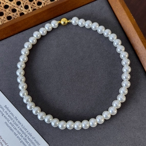 Close-up of elegant white round pearl necklace with decorative gold magnetic clasp