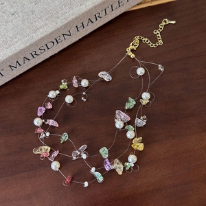 Detailed close-up of pink natural stones and pearl beaded necklace with gold chain clasp