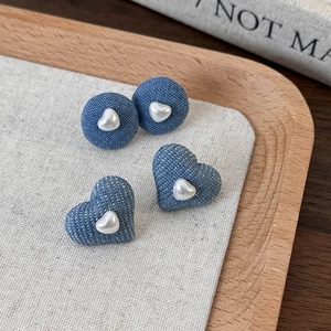 Detail of light blue denim fabric heart and round earrings with white pearl centers
