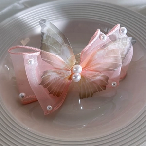 Detail of pink gradient organza butterfly hair clip with elegant pearl beads on white tray