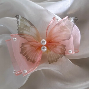 Detail of pink tulle butterfly hair clip with delicate pearl edges on silk fabric
