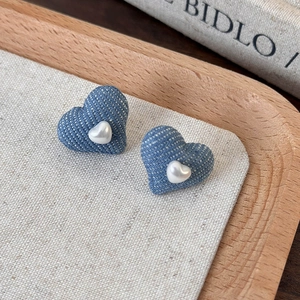 Detail of vintage denim heart stud earrings featuring a small pearl center ornament