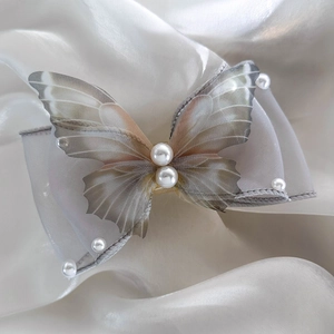Detailed view of the butterfly hair clip featuring realistic wings and pearl accents