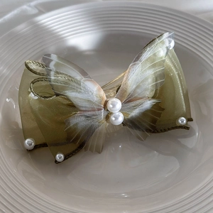 Detail of a large olive green gauze butterfly hair clip with pearls and mesh wings