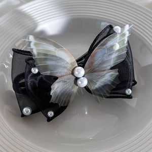 Detail view of a 3D butterfly hair clip with black mesh layers and white pearls