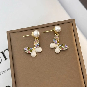 Elegant butterfly stud earrings with colorful crystals and pearls on a premium jewelry box