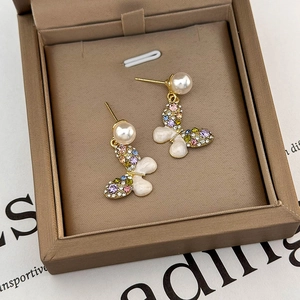 Detailed macro of golden butterfly earrings with colorful rhinestones and pearls