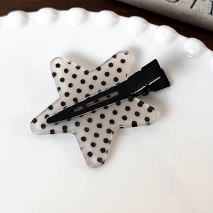 Dettaglio di un fermaglio per capelli a forma di stella a pois su un piatto bianco