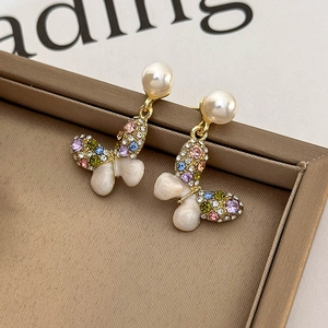 Close-up of butterfly earrings with colorful rhinestones, pearls, and gold metal finish